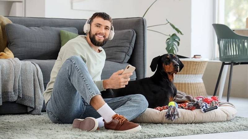 Young,Man,In,Headphones,With,Mobile,Phone,And,Dobermann,Dog