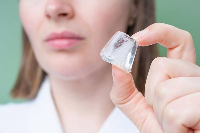 Young,Woman,Holding,Ice,Cube,Near,Her,Face,On,Green