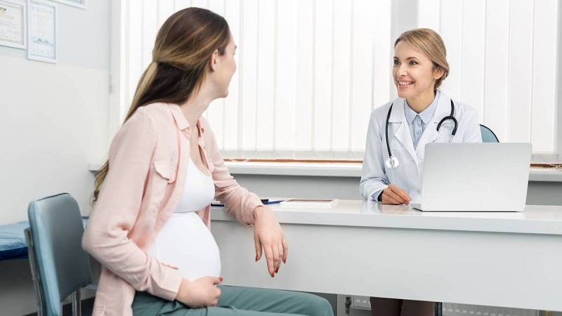 Mladá těhotná žena na konzultaci s gynekoložkou